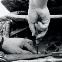 Close-up of the hands of a craftsman at work on the seat of a club chair