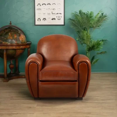 Raymond club armchair in havana basane leather, rounded backrest and sculpted armrests, front view in a styled interior setting