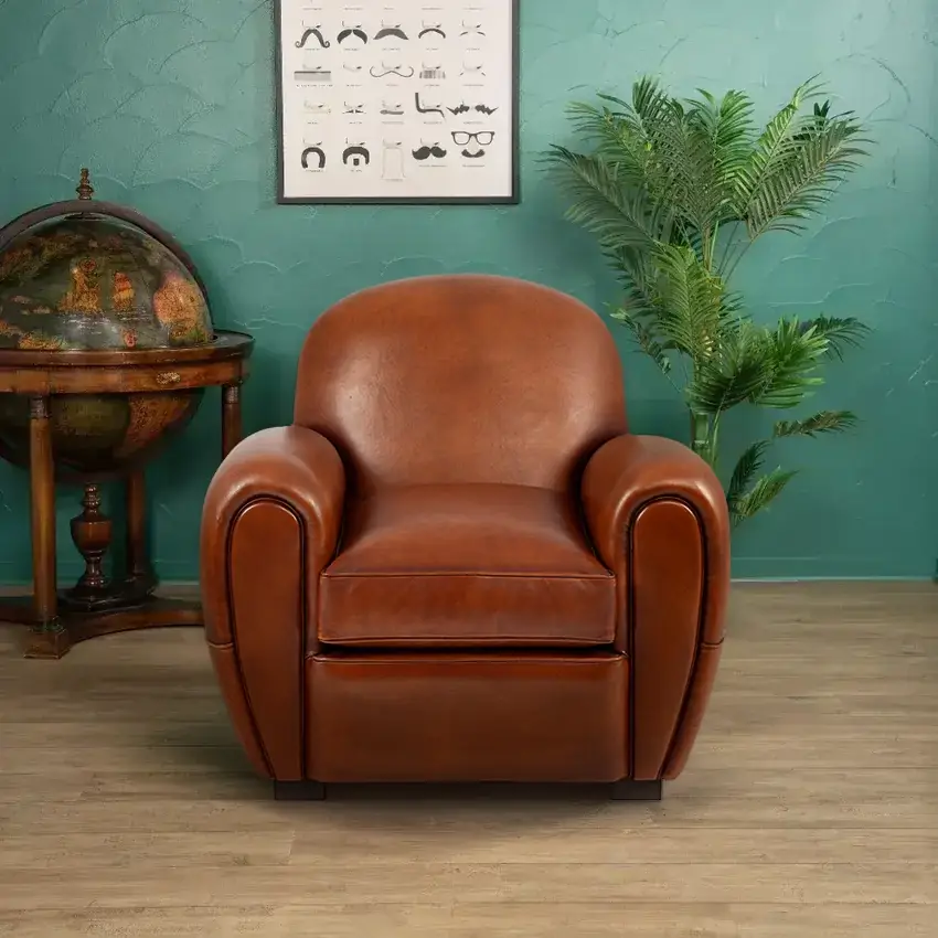 Raymond club armchair in havana basane leather, rounded backrest and sculpted armrests, front view in a styled interior setting