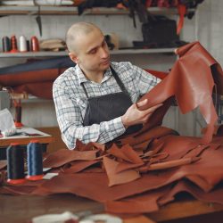 A craftsman examines a piece of basane leather in his hands